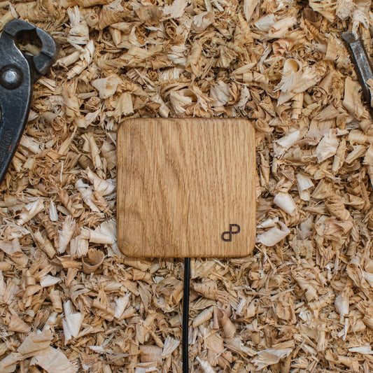 Handcrafted wooden wireless charger on wood shavings, showcasing elegant design and eco-friendly materials.