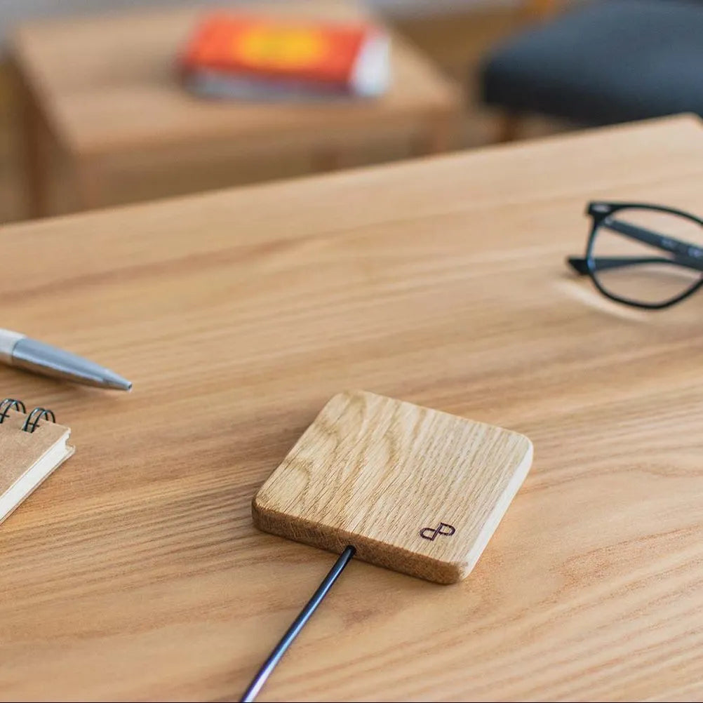 Handcrafted wooden wireless charger on a table with stationery, showcasing a sleek and elegant design.