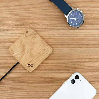 Handcrafted wooden wireless charger with smartphone and watch on a wooden surface, showcasing its elegant design and functionality.